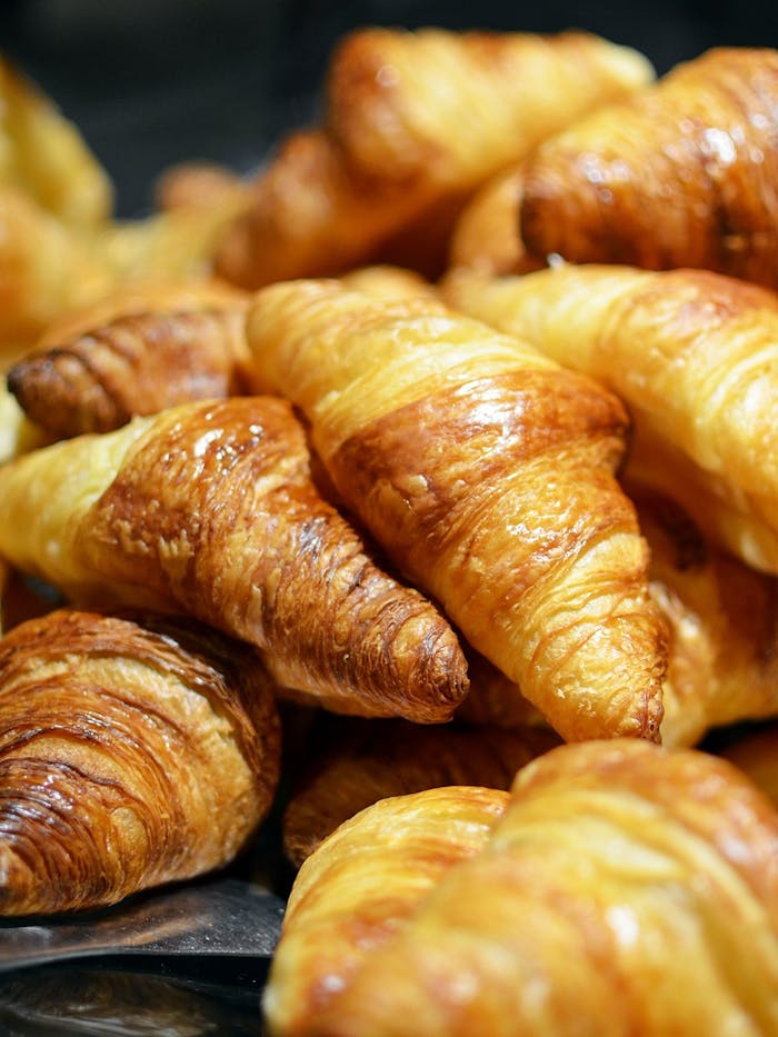 food france morning breakfast A stack of golden, freshly baked croissants showcasing flaky layers in a bakery setting.